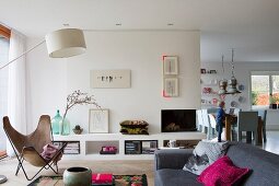 Butterfly chair, standard lamp and low masonry sideboard in open-plan interior