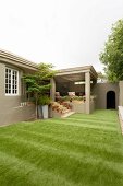 Large area of artificial lawn outside cubic house with steps leading to veranda
