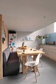 Comfortable kitchen-dining room with wooden table, upholstered bench and white Eames Chairs