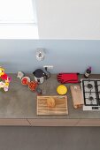 Blick von oben auf Küchenzeile mit hellblauem Spritzschutz, Gaskochfeld und Küchenutensilien