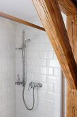 Old wooden beams in front of shower with subway tiles