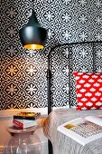 Black vintage metal bed and pendant lamps against tiled wall with black and white floral pattern in bedroom