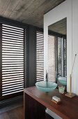 Waschbereich mit minimalistischem Waschtisch, Glasschüssel auf Holztisch, gegenüber Terrassentür mit geschlossenem Holzlamellen
