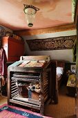 Vintage wooden lectern at foot of bed and floral wall hanging on sloping ceiling above bed in attic bedroom