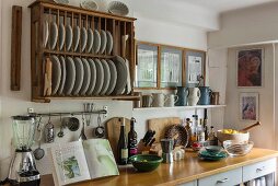 An Wand rustikaler Geschirrtrockner aus Holz mit weißem Geschirr über Küchenzeile in ländlicher Küche