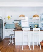 Island counter, bar stools and two paint-dipped wicker pendant lamps in modern kitchen