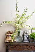 Magnificent orchid branches in a glass vase, tins with shell decoration and handcrafted lantern on a Balinese console table