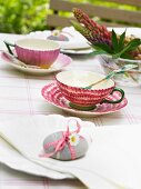 Pebble with ribbon and flower used as napkin weight on summery table set for afternoon tea
