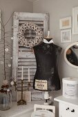 Vintage tailors' dummy and candelabra in front of wreath on detached window shutter