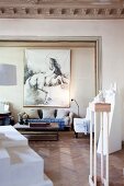 White, modern artworks on plinths in historical building with open doorway and view of large picture of horse in lounge