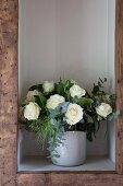 Bouquet of white roses in shelf compartment with wooden frame