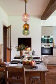 Set dining table, various chairs and pendant lamp with spherical glass lampshades in kitchen