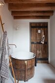Rustic wooden tub and wooden door with wrought iron fittings in small bathroom