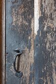 Schmiedeeiserner Griff an Holztür mit abblätternder Farbe
