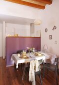 Gedeckter Tisch vor Theke mit violetten Paneelen, seitlich an Wand Deko Buchstaben