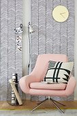 A pastel pink swivel chair contrasting with the geographic black-and-white patterns on the wallpapered wooden panels and cushion