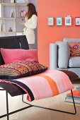A living room with upholstered seats in black and grey complemented by a mixture of patterns in pink and coral