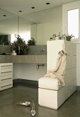 L-shaped concrete washstand with base cabinet, half-height partition with tip-on drawers and integrated stool