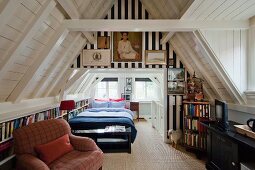 Narrow, multifunctional attic room with TV chair, fitted shelving at knee wall height and double bed