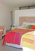 Patchwork bedspread on double bed against partition in bedroom