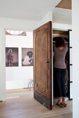 Frau vor Kleiderschrank hinter geöffneter Holztür, im Vorraum Fotokunst mit Frauenmotiv
