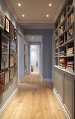 Narrow hallway with fitted cupboards and shelves below suspended ceiling with recessed spotlights in traditional interior