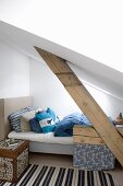 Scatter cushions on bed and wooden cube table under sloping ceiling