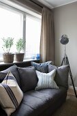 Dark grey sofa with scatter cushions and retro-style standard lamp below window