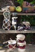 Bottles and jam jars in macrame covers on weathered wooden shelves in autumn