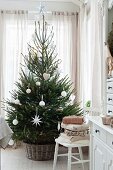 Weiß geschmückter Weihnachtsbaum vor Fenster
