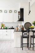 Black bar stools at counter in white country-house kitchen