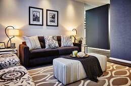 Polstertisch vor dunklem Sofa mit verschiedenen Kissen in beleuchtetem elegantem Wohnzimmer mit Mustermix