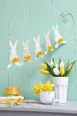 Easter arrangement in pastel shades; garland of paper bunnies, vases of narcissus and tulips