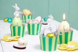 Easter arrangement in yellow and green; candles and sweets in stripe muffin cases