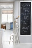 Message on blackboard in white foyer and view into kitchen with lattice window and vintage ambiance