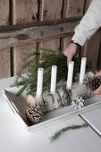 Four white candles in DIY candelabra made from half a birch log and glass drip catchers