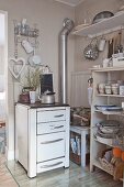 Old cooker and open-fronted shelves of crockery in vintage-style kitchen