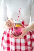 Woman holding jar of home-made raspberry lemonade