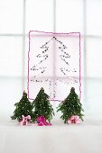 Christmas tree motif made from silver stars on translucent fabric and miniature Christmas trees with pink ribbons