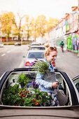 Urban Gardening: Junge Frau mit Grün-und Gemüsepflanzen in Cabrio