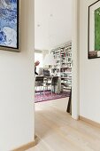 Blick vom Vorraum durch offene Tür in Wohnraum mit Arbeitsplatz, an Wand Bücherregale