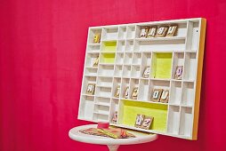 White-painted display case with yellow accents on side table leaning against hot pink wall