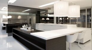 Designer kitchen with black and white elements - pendant lamps above table top mounted across wooden counters