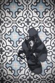 Ladies' black sandals on tiled floor with ornamental pattern