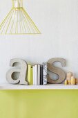 Decorative concrete letters used as bookends on shelf on wall