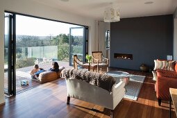 Elegant, traditional interior with leather sofa, antique chairs and dark grey wall; family sitting in warm spring sunshine on balcony with view of landscape