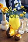 Vase of gerbera daisies and freesias, china dogs and tealight holders on coffee table