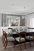 Large square glass table and various upholstered wooden chairs in dining room