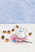 Paintbrushes, coffee pot painted with porcelain paint and cake pops with colourful decoration