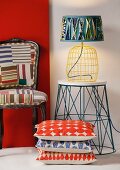 Stacked patterned cushions in front of table lamp on side table next to char with graphic patterns on upholstery